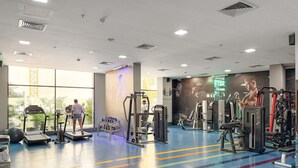 Una palestra con tapis roulant, macchinari per pesi e una grande vetrata.