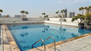 Una piscina sul tetto con vista panoramica sulla skyline della città, circondata da piante in vaso.