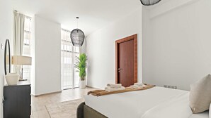 Una moderna camera d'albergo con un letto grande, una porta in legno, una pianta in vaso e una scrivania con una lampada.