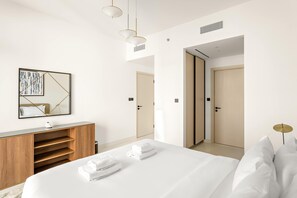 A modern hotel room with a large bed, a wooden dresser, and a mirror with a geometric design. - Silkhaus Large 2bdr Sea View Emaar Tower (Dubai)