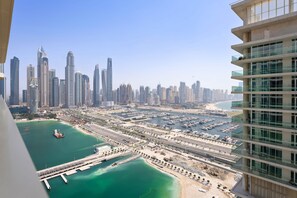 A high-rise hotel overlooking a marina with multiple boats, a clear sky, and a cityscape in the background. - Marina Apartment w Building Pool gym Balcony (Dubai)