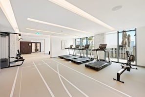A gym with treadmills, a rowing machine, and a stationary bike. - Marina Apartment w Building Pool gym Balcony (Dubai)