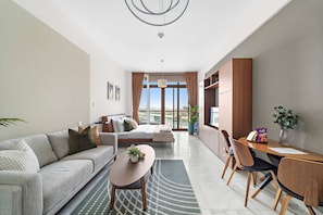 A modern living room with a sofa, coffee table, and dining area with chairs and a table. - Silkhaus Chic Studio in Palm Jumeirah Sea View (Dubai)