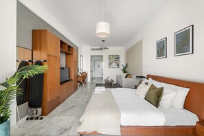 A modern hotel room with a large bed, a wooden wardrobe, a TV, a seating area with a table and chairs, and artwork on the walls. - Silkhaus Chic Studio in Palm Jumeirah Sea View (Dubai)
