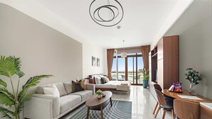 A modern living room with a sofa, coffee table, and dining area. - Silkhaus Chic Studio in Palm Jumeirah Sea View (Dubai)