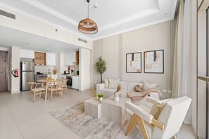 Ein geräumiger Wohnbereich mit Esstisch, Sofa und Couchtisch. Im Hintergrund ist eine Küche mit modernen Geräten zu sehen.