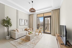 A modern living room with a sofa, coffee table, and chairs, a TV on a wooden stand, and a large window with a city view. - Silkhaus Chic and Cozy 1 BDR In Reem Island (Abu Dhabi)