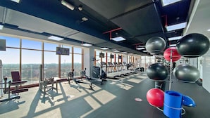 A gym with exercise equipment, large windows, and a view of the city. - Silkhaus Chic Studio With Pool and Gym (Dubai)