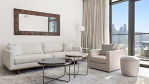 Ein modernes Wohnzimmer mit einer Couch, einem Sessel, einem runden Couchtisch und einem großen Spiegel an der Wand.