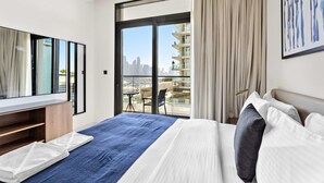 Ein Hotelzimmer mit Bett, Fernseher, einem Balkon mit Blick auf die Stadt und einem Schreibtisch.