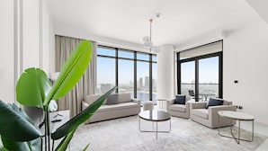 A modern living room with a large sofa set, two round coffee tables, and a view of the city through large windows. - Silkhaus Spacious 2BR Marina Vista Tower Beach (Dubai)