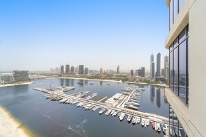 A marina with numerous boats docked, a city skyline in the background, and a clear sky. - Silkhaus Spacious 2BR Marina Vista Tower Beach (Dubai)