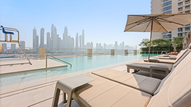 A rooftop pool with lounge chairs and an umbrella, overlooking a city skyline. - Silkhaus Spacious 2BR Marina Vista Tower Beach (Dubai)