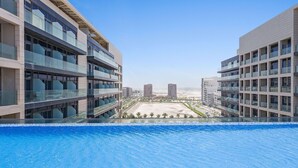 Ett modernt hotell med en pool som har utsikt över en strand och stadens skyline.