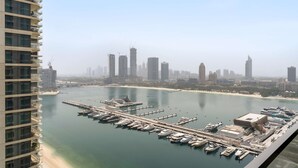 A marina with numerous boats docked, a pier, and a city skyline in the background. - Silkhaus Luxurious 1bdr With Sea View in Emaar (Dubai)