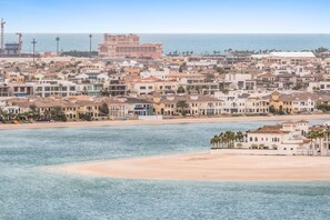 A coastal cityscape with a beachfront, buildings, and a large pink structure in the background. - Silkhaus Luxurious 1bdr Sunset Sea View (Dubai)
