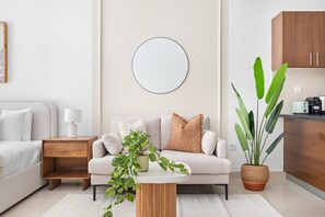 A modern living room with a sofa, a coffee table, a side table, and a potted plant. - Silkhaus Stylish Studio Nova Tower in DSO (Dubai)