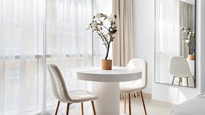 A modern room with a round white table, two white chairs, a potted plant, and a large mirror on the wall. - Silkhaus Stylish Studio Nova Tower in DSO (Dubai)
