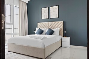 A modern bedroom with a large bed, a nightstand, and a window with curtains. - Silkhaus Horizon Tower Big 1bdr Near Al Fay Park (Abu Dhabi)