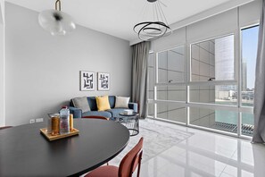 Ein modernes Wohnzimmer mit Esstisch, Sofa und großen Fenstern mit Blick auf die Stadt.
