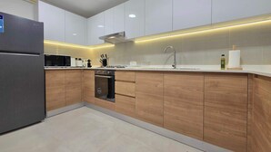 A modern kitchen with white cabinets, a stainless steel refrigerator, and a built-in oven. - Silkhaus Serene 1bdr Apartment Al Reem Island (Abu Dhabi)