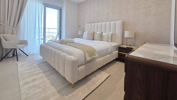 A modern hotel room with a large bed, a sitting chair, a nightstand, and a view of the city. - Silkhaus Serene 1bdr Apartment Al Reem Island (Abu Dhabi)