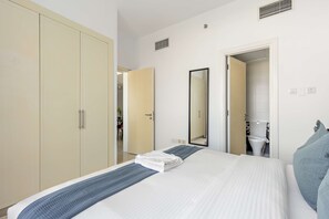 A hotel room with a bed, a wardrobe, a bathroom, and a mirror. - Silkhaus Sea View 2bdr Retreat Oceanscape (Abu Dhabi)