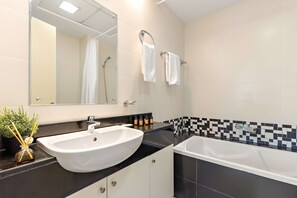 A modern bathroom with a large white sink, a bathtub, and a mirror above the sink. - Silkhaus Sea View 2bdr Retreat Oceanscape (Abu Dhabi)