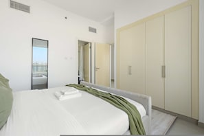 A modern hotel room with a large bed, a wardrobe, and a mirror. - Silkhaus Sea View 2bdr Retreat Oceanscape (Abu Dhabi)
