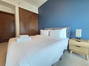 A hotel room with a large bed, a wardrobe, a bedside table, and a nightstand. - Silkhaus Signature 1BR in Reem Island Gate Tower (Abu Dhabi)