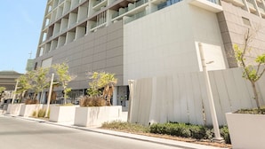 A tall, modern building with multiple balconies, a flat facade, and a clear sky. - Silkhaus 1BR Elegant Living In Maryah Vista (Abu Dhabi)