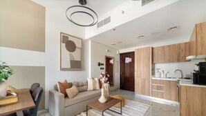 A modern living room with a sofa, coffee table, and a dining area with a table and chairs. - Silkhaus 1BR Elegant Living In Maryah Vista (Abu Dhabi)