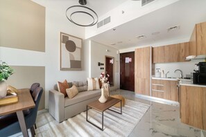 A modern living room with a sofa, coffee table, and a dining area with a table and chairs. - Silkhaus 1BR Elegant Living In Maryah Vista (Abu Dhabi)