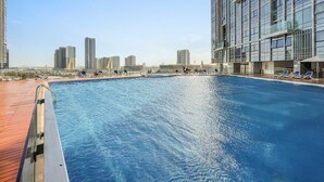 A rooftop pool with lounge chairs and a city skyline in the background. - Silkhaus Premier 2BR Stay Near Reem Central Park (Abu Dhabi)