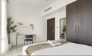 Un dormitorio moderno con cama, escritorio y armario.