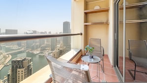 A balcony with a view of a cityscape and river. There are two chairs and a small table with a plant. - Silkhaus Iconic 2bdr Near Jumeirah Beach Resort (Dubai)