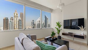Uma sala de estar moderna com uma grande janela, uma televisão de tela plana, um sofá, uma mesa de centro e um vaso com planta.