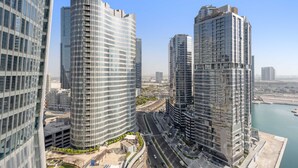 Un quartier urbain dense, avec de grands immeubles modernes, une route et une étendue d’eau.