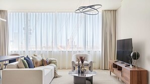 A modern living room with a sofa, armchair, coffee table, TV, and wooden console. - Silkhaus Cityscape in Sky Gardens Metro Access (Dubai)