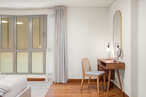 A bedroom with a bed, a wooden desk with a chair, a large mirror, and a window with curtains. - Silkhaus Exclusive 1bdr Stay Sky Gardens in Difc (Dubai)