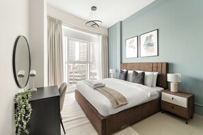Ein modernes Schlafzimmer mit einem großen Bett, Nachttischen, einem Schreibtisch und einem Fenster mit Vorhängen.