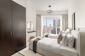 Ein modernes Hotelzimmer mit großem Kleiderschrank, einer Schlafcouch, einem großen Fenster mit Blick auf die Stadt und einer Hängelampe.