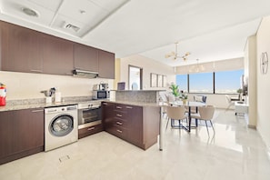 A modern kitchen with built-in appliances, a dining area with a view, and a clean, minimalist design. - Silkhaus Deluxe 1BR Stay in Sky Gardens in Difc (Dubai)
