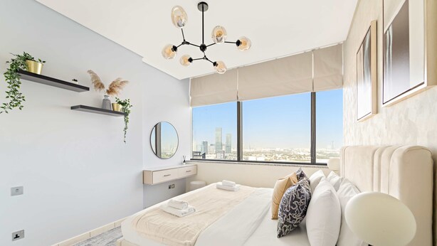 A modern bedroom with a large bed, a city view, a chandelier, and minimalist decor.