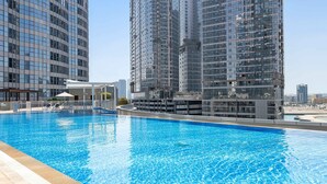 Una piscina con borde de baldosas, rodeada de edificios altos, algunos en construcción.