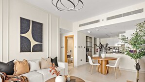 A modern living room with a sofa, coffee table, and dining area. - Silkhaus Lavish 3bdr Stay in Radiant Boulevard (Abu Dhabi)
