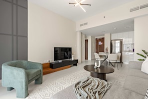 A modern living room with a sofa, a TV, a dining area, and a kitchen. - Silkhaus New 1bdr Minutes Walk to Reem Beach (Abu Dhabi)