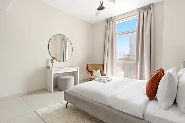 A modern bedroom with a large bed, a round mirror, a desk, and a chair. - Silkhaus New 1bdr Minutes Walk to Reem Beach (Abu Dhabi)