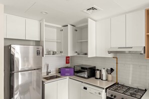 A modern kitchen with white cabinets, a stainless steel refrigerator, a microwave, a gas stove, and a dishwasher. - Silkhaus New 1bdr Minutes Walk to Reem Beach (Abu Dhabi)