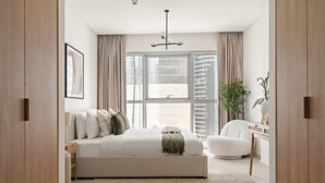 A modern bedroom with a large bed, a bedside table, a chair, and a window with curtains. - Silkhaus Brand New 1bdr Radiant Reem Island (Abu Dhabi)